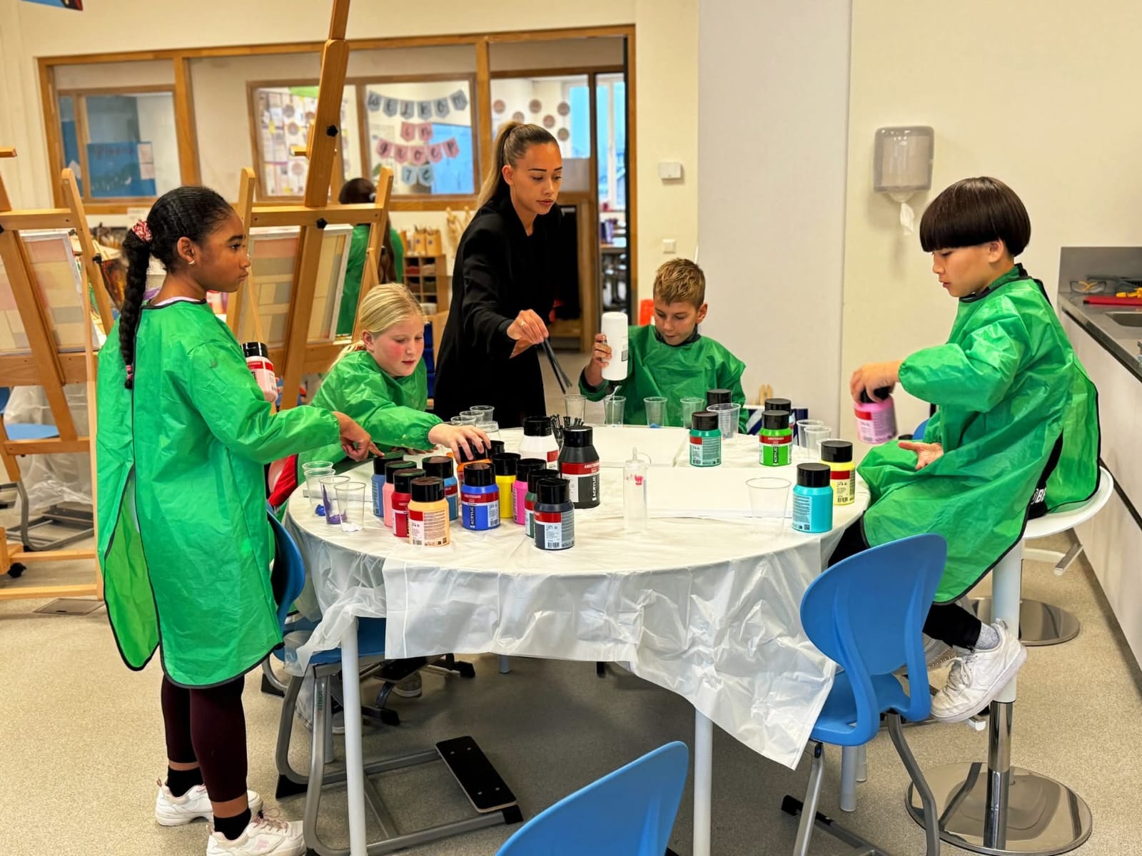 Groep kinderen werkt samen aan een Art Pouring workshop onder begeleiding