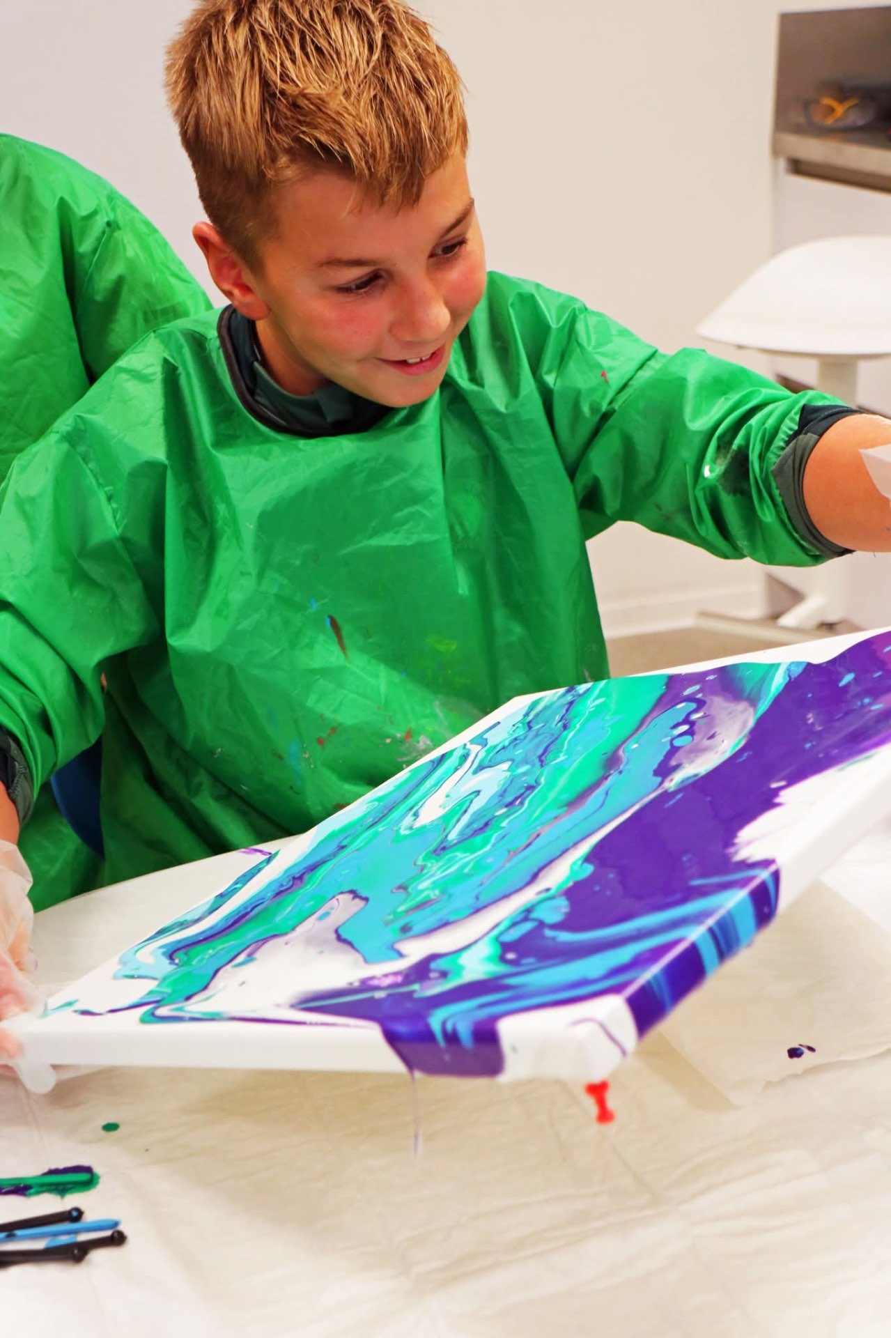 Jongen lacht trots terwijl hij zijn paars-turquoise kunstwerk toont