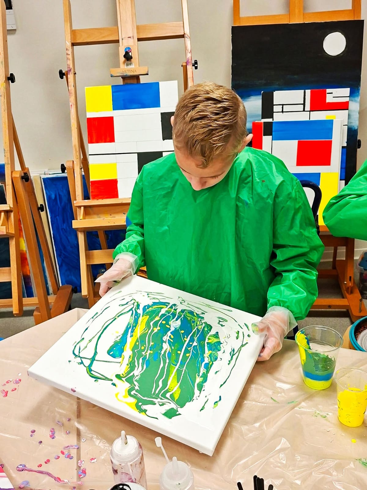 Deelnemer toont zijn groen-gele pouring kunstwerk