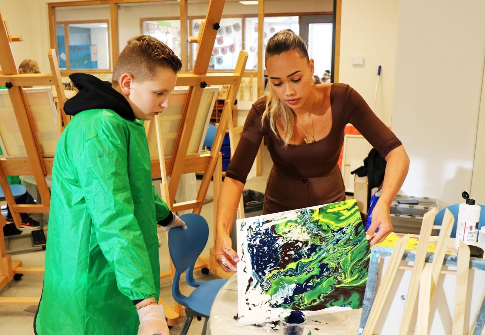 Workshopbegeleider werkt samen met een deelnemer aan een Art Pouring kunstwerk
